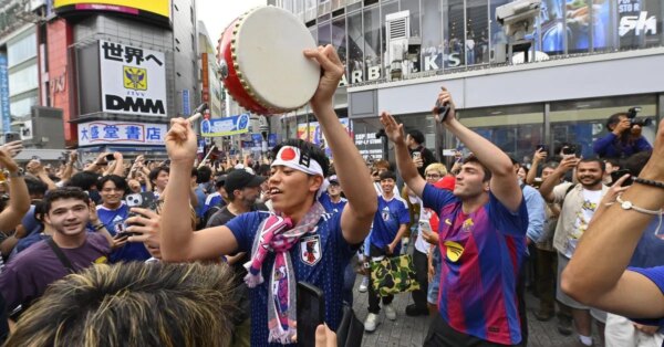 Os torcedores do Japão comemoram a vitória da Copa do Mundo da FIFA sobre a Tunísia ao assumir o icônico cruzamento de Shibuya em Tóquio